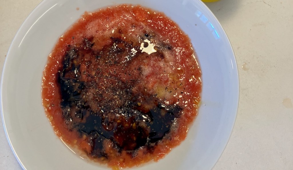 Geriebene Tomaten in einer Schale mit Balsamico, Pfeffer und Olivenöl
