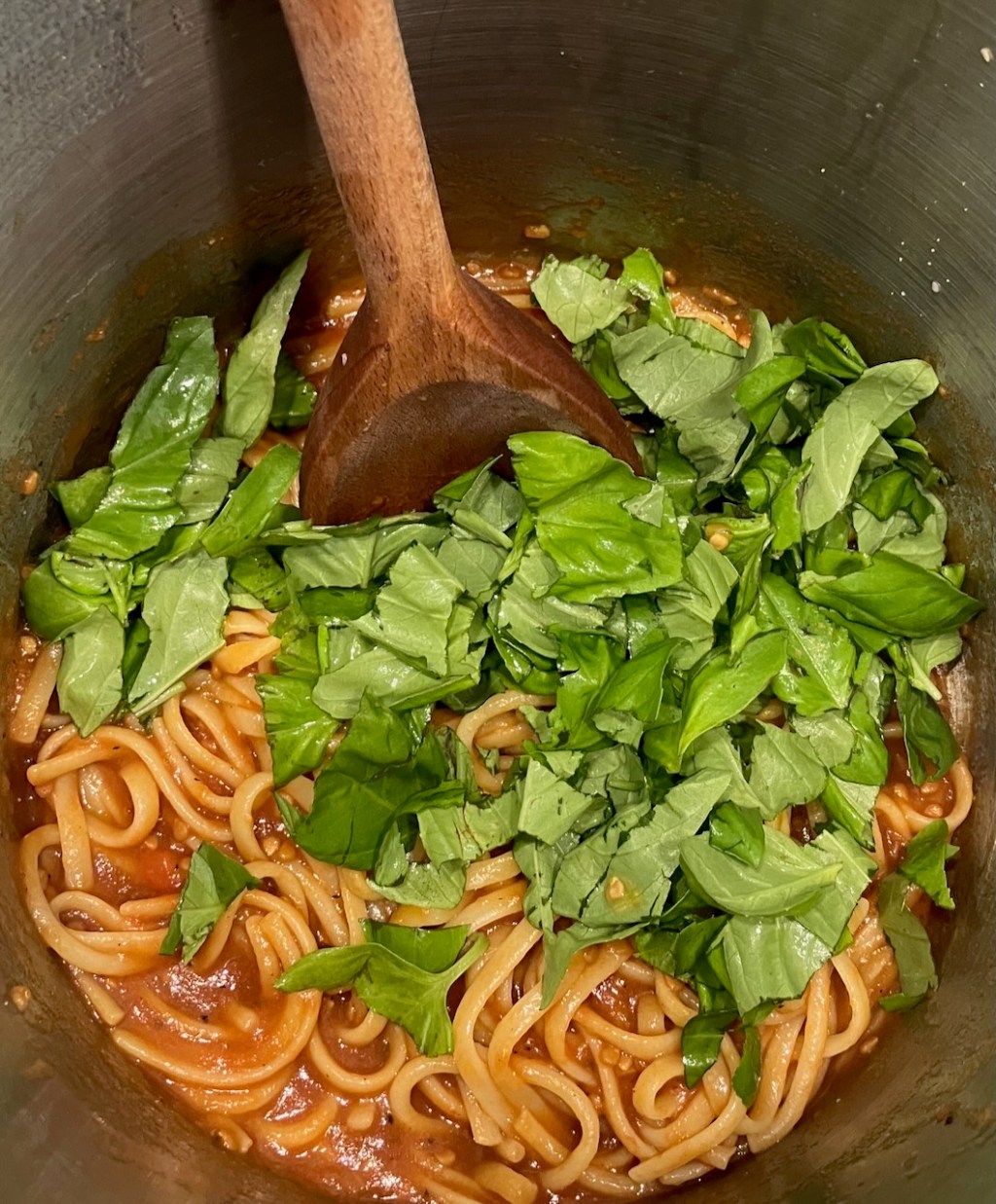 Linguine in Tomatensauce im Topf, oben gehacktes Basilikum